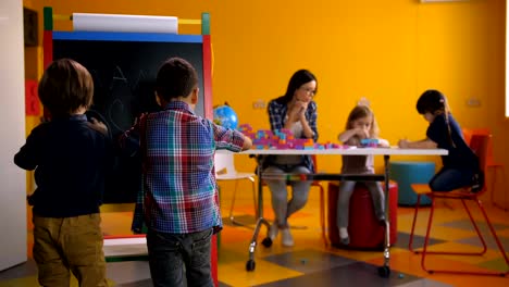 Engrossed-boys-drawing-with-chalks-at-blackboard