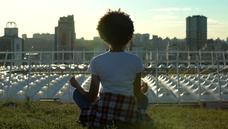 Entspannte-afroamerikanische-Frau-sitzt-in-Lotus-Pose,-Meditation-bei-Sonnenuntergang,-rest