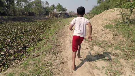 Village-boys-run-happily-through-green-field-toward-bridge.-2X-slow-motion.