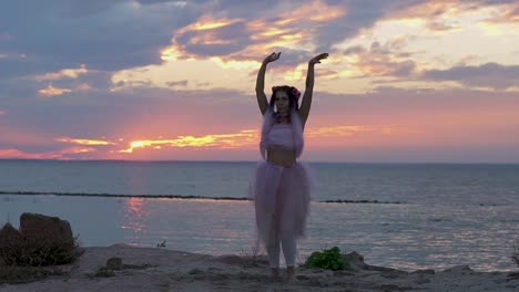 Mujer-linda-con-maquillaje-brillante-en-un-vestido-rosa-bailando-en-la-orilla-del-río.-El-baile-de-una-chica-sensual-con-un-peinado-maravilloso-con-flores.-Cámara-lenta.