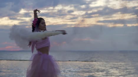 Cute-girl-with-sparkling-makeup-in-a-pink-dress-dancing-on-the-bank-of-the-river.-The-dance-of-a-sensual-woman-with-a-wonderful-hairstyle-with-flowers.-Slow-motion.