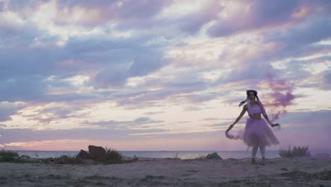 Beautiful-young-woman-with-sparkling-makeup-in-a-pink-dress-dancing-with-smoke-bombs-on-the-bank-of-the-river.-The-dance-of-a-sensual-girl-with-a-wonderful-hairstyle-with-flowers.-Slow-motion.