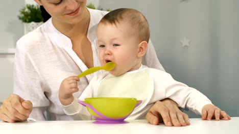 Baby-mit-Schüssel-und-Löffel-versuchen-zu-essen