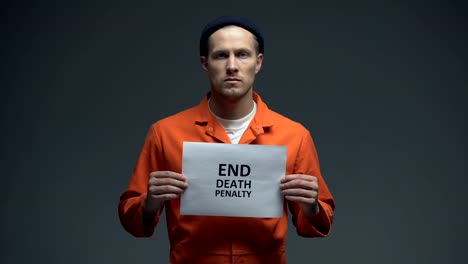 Caucasian-male-prisoner-holding-End-death-penalty-sign-in-cell,-asking-for-help