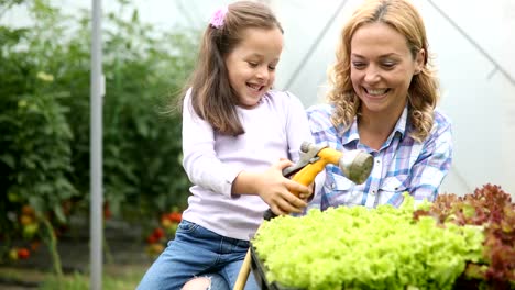 Concepto-de-cultivo,-jardinería,-agricultura-y-personas.-La-madre-feliz-y-su-hija-trabajando-en-invernadero