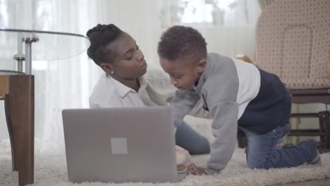 Mujer-afroamericana-con-su-lindo-hijo-mirando-la-Laptop.