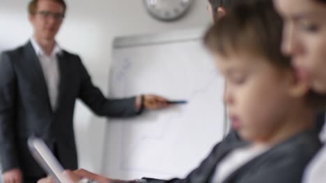 Madre-e-hijo-jugando-en-la-tableta-durante-la-reunión-corporativa