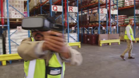 Male-warehouse-worker-using-VR-headset-and-controller-in-loading-bay-4k