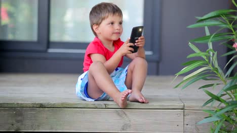 Kleiner-niedlicher-Junge-macht-ein-Foto-mit-Handy