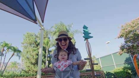 POV-sliding-on-slide-at-playground-to-meet-mother-with-baby-on-carrier