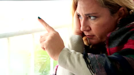 Sad-young-woman-looking-through-window