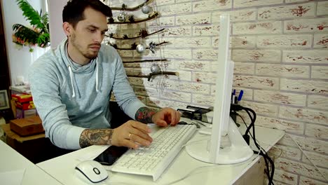 Young-bearded-businessman-in-grey-sweatshirt-working-in-bright-office.