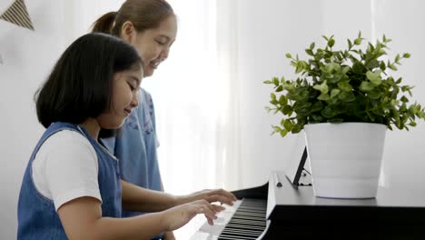 4K-:-Slow-motion-of-Asian-girl-playing-piano-with-her-mother,-Zoom-in-shot