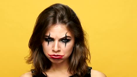 Upset-brunette-lady-with-creepy-make-up-for-halloween-looking-camera-isolated-over-yellow