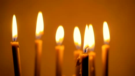 Close-up-of-a-lot-of-beautiful-wax-candles-burning.-Yellow-background.