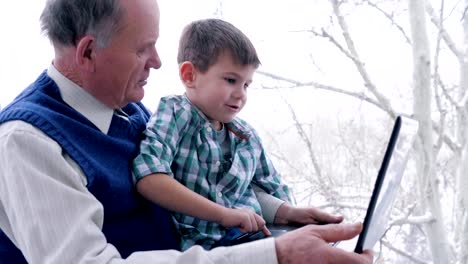 preschool-home-education,-old-man-with-child-with-laptop-in-hand-indoors