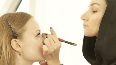 Frau-Make-up-Artist,-die-Anwendung-Ton-Creme-mit-Kosmetik-Pinsel-auf-Schönheit-Hautmodell-in-Umkleidekabine.-Professionelle-Make-up-Frau-Gesicht-auf-Lektion-während-Meisterklasse-in-Schönheitsschule