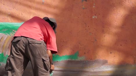 Pintor-mural-dibuja-imágenes-en-color-en-la-pared-de-la-escuela