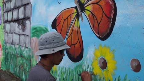 Pintor-mural-pinta-mariposa-en-color-en-la-pared-de-la-escuela.