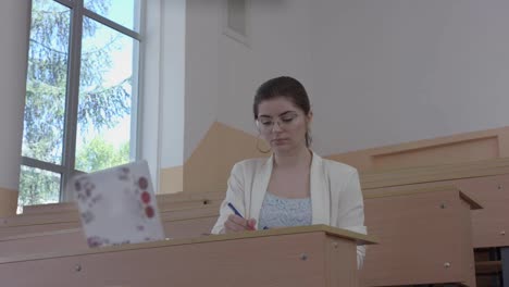 Feliz-niña-sonriente-con-gafas-sentado-en-aula.