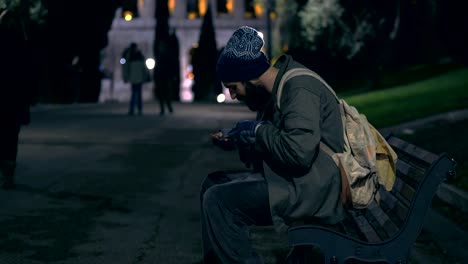 hungry-beggar-on-bench-at-night-counting-his-money