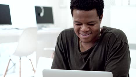Mittlere-Schuss-schwarzen-jungen-Mann-lächelnd-während-SMS-im-sozialen-Netz-im-Internet-café