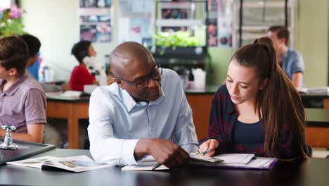 High-School-Lehrer-sitzen-am-Schreibtisch-mit-Studentin-im-Biologieunterricht