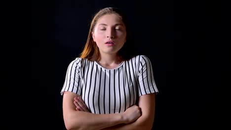 Furious-young-woman-standing-with-crossed-hands-and-looking-at-camera-with-angry-and-concerned-expression,-black-background