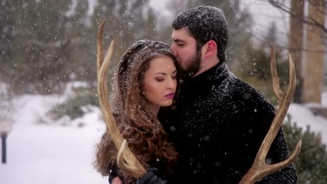 Couple-in-black-clothes-under-heavy-snow.-Wedding.