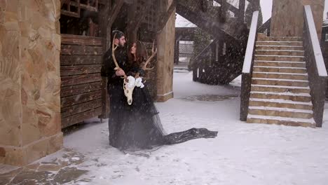 A-loving-couple-in-black-clothes-under-a-snowfall.