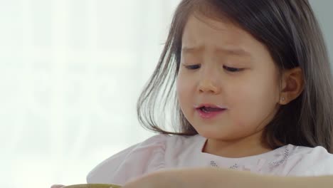 Niña-asiática-comiendo-galletas-y-leche