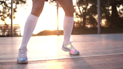 Cerca-de-las-piernas-de-jugador-de-baloncesto-femenino-en-calcetines-de-golf-blanco-haciendo-bueno-regate-muy-rápidamente,-correr-hacia-atrás,-al-aire-libre-en-la-formación-en-la-corte-local.-Sol-brilla-en-el-fondo