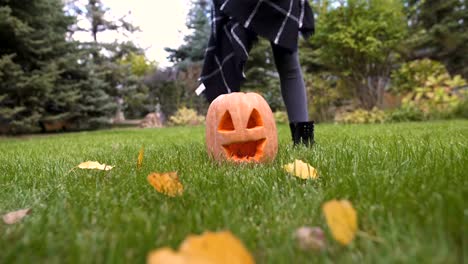 Happy-girl-taking-pumpkin-Jack-in-hands,-playing-in-yard,-Halloween-celebration