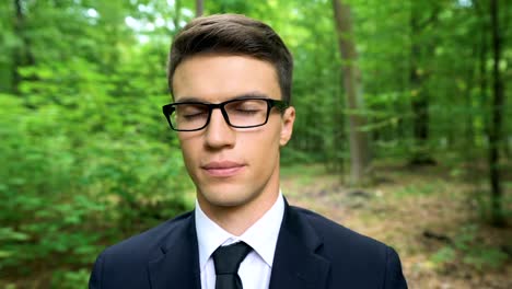 Calm-businessman-sitting-with-legs-crossed-and-eyes-closed-on-desk-in-forest