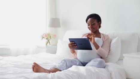 happy-pregnant-woman-with-tablet-pc-in-bed