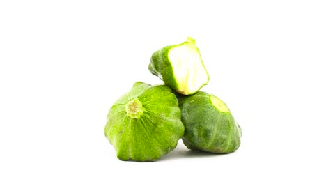 Zwei-ganze-grüne-Pattypan-Kürbisse-und-eine-Hälfte-Schnitt-Patty-pan-squash.-Drehen.-Auf-dem-weißen-Hintergrund-isoliert.-Close-up.-Makro.