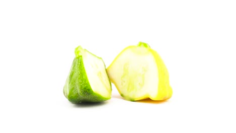 Two-halves-of-green-and-yellow-pattypan-squashes.-Rotating.-Isolated-on-the-white-background.-Close-up.-Macro.