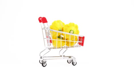 Carrito-de-supermercado.-Carro-de-compras-con-calabaza-de-pattypan-amarillo.-Movimiento-en-el-marco.-Aislado-sobre-fondo-blanco.-Close-up.-Macro.