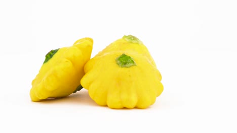 Zwei-ganze-gelbe-Pattypan-Kürbisse.-Auf-dem-Plattenteller-drehen.-Auf-dem-weißen-Hintergrund-isoliert.-Close-up.-Makro.