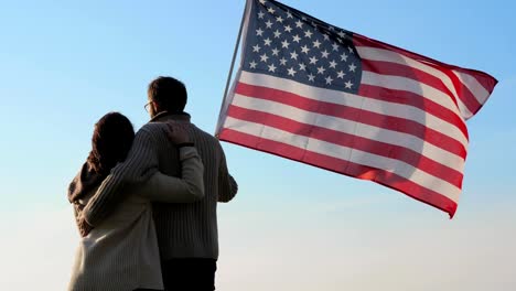 Patriotischen-Familie-mit-eine-große-Fahne-von-Amerika-in-der-Hand-im-freien