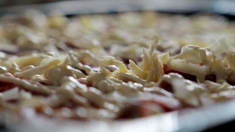 Cheese-falls-on-the-sauce-and-salami-delicious-and-appetizing-pizza,-close-up.-The-concept-of-pizza