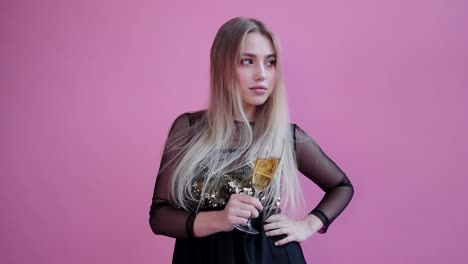 Pretty-girl-wear-red-horns,-hold-a-glass-of-champagne-and-pose-to-camera-in-pink-background-studio