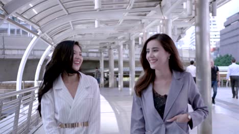 Female-Business-People-Walk-and-Discuss-Business-and-smiling-happily-in-city-centre-Thailand.-SLOW-MOTION