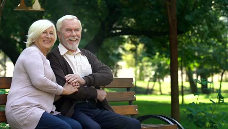 Altes-Paar-auf-Bank-sitzen-und-beobachten-gerne-ihre-Enkel-Spaß