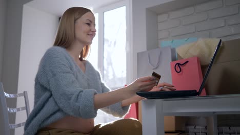 Pago-por-Internet,-hermosa-mujer-expectante-con-tarjeta-de-crédito-utiliza-el-ordenador-portátil-para-compras-en-línea-en-Internet