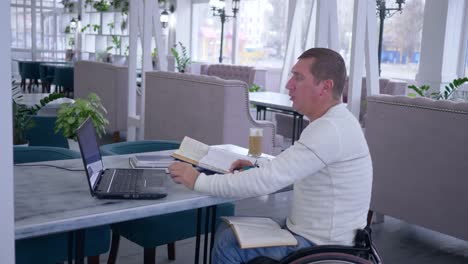 e-learning-of-disabled,-ill-student-male-on-wheel-chair-uses-modern-computer-technology-to-distance-studying-from-online-lecture-and-books-making-notes-in-notebook