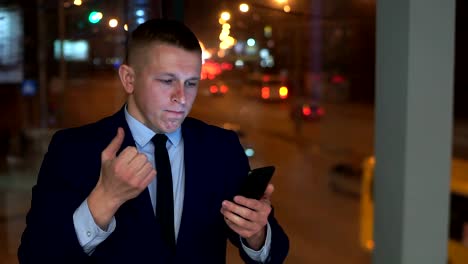 The-man-is-a-businessman,-looking-at-the-smartphone-and-angry,-trying-to-contain-anger.
