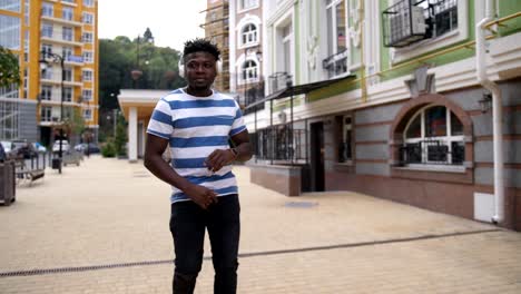 Joyful-black-man-enjoying-music-on-city-street