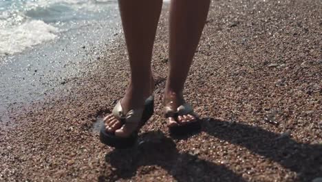 Woman's-legs-in-flip-flops-on-beach.