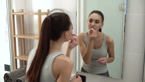 Maquillaje.-Mujer-aplicar-lápiz-labial-líquido-en-boca-en-el-baño